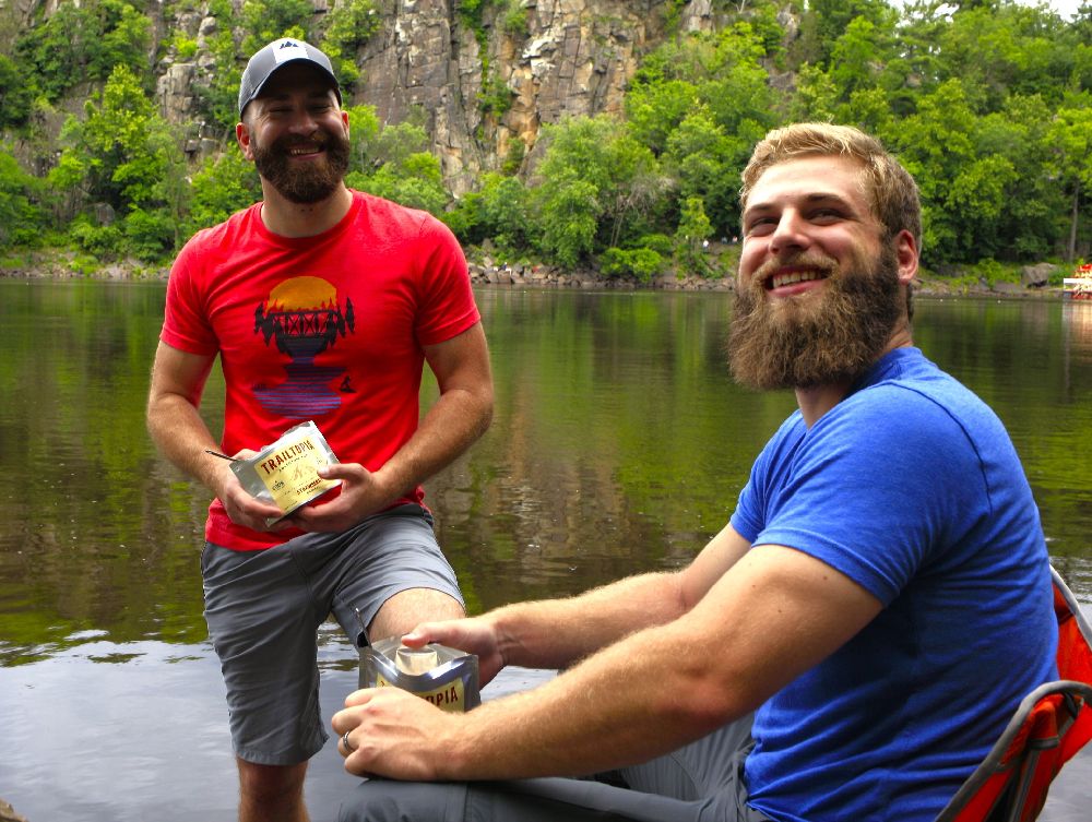 Friends Enjoying Breakfast Near Lake - Trail Food Mistakes - Trailtopia